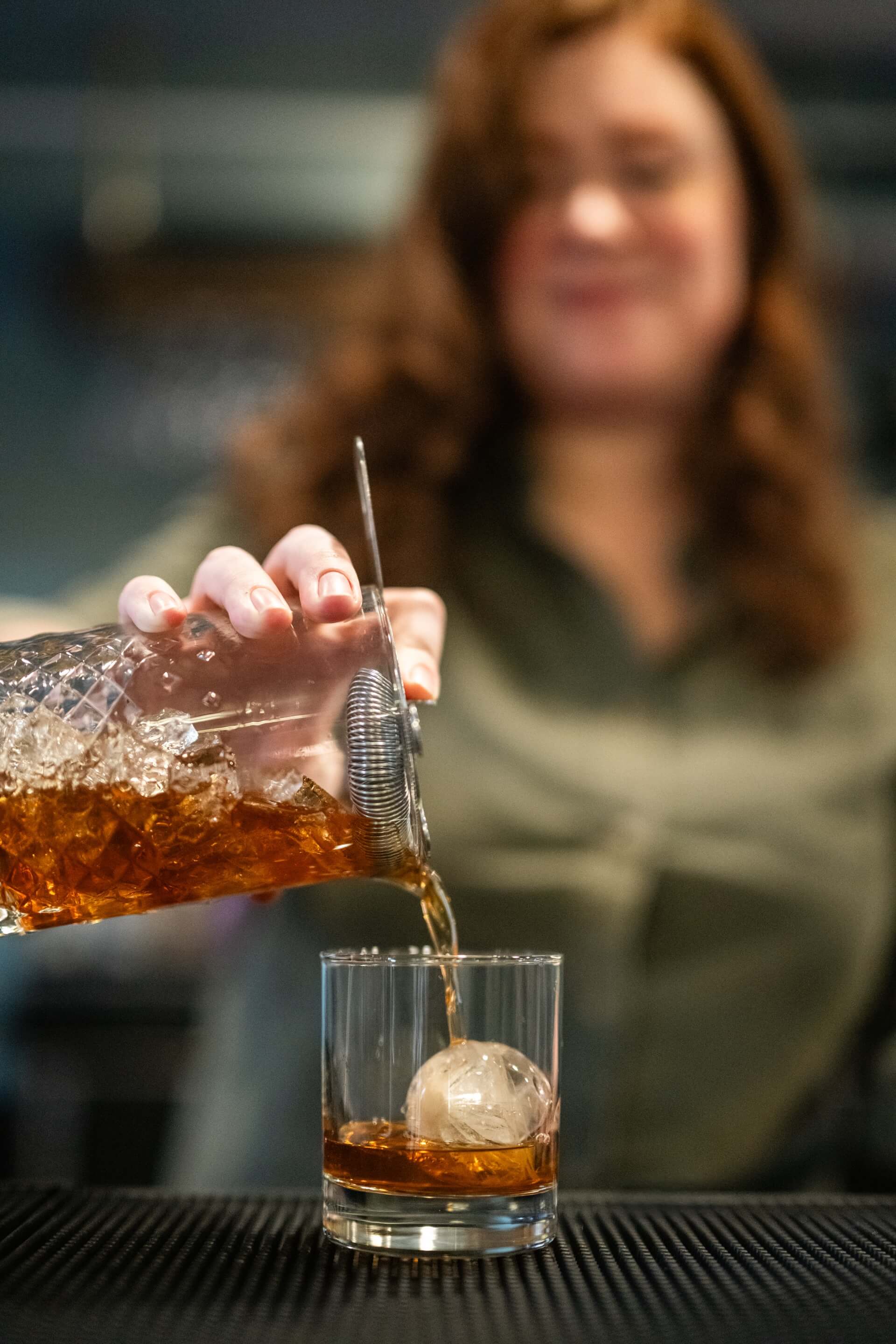 a bartender pouring a drink into a glass